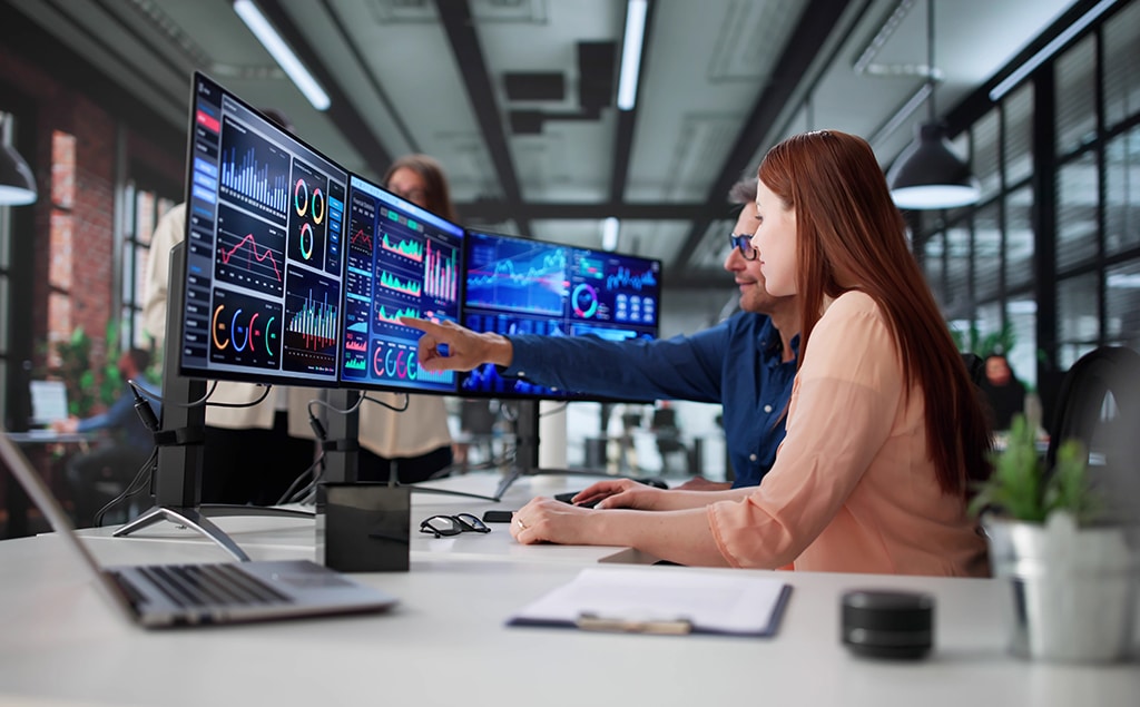 IT professionals analyzing network performance dashboards and cybersecurity metrics on multiple monitors.